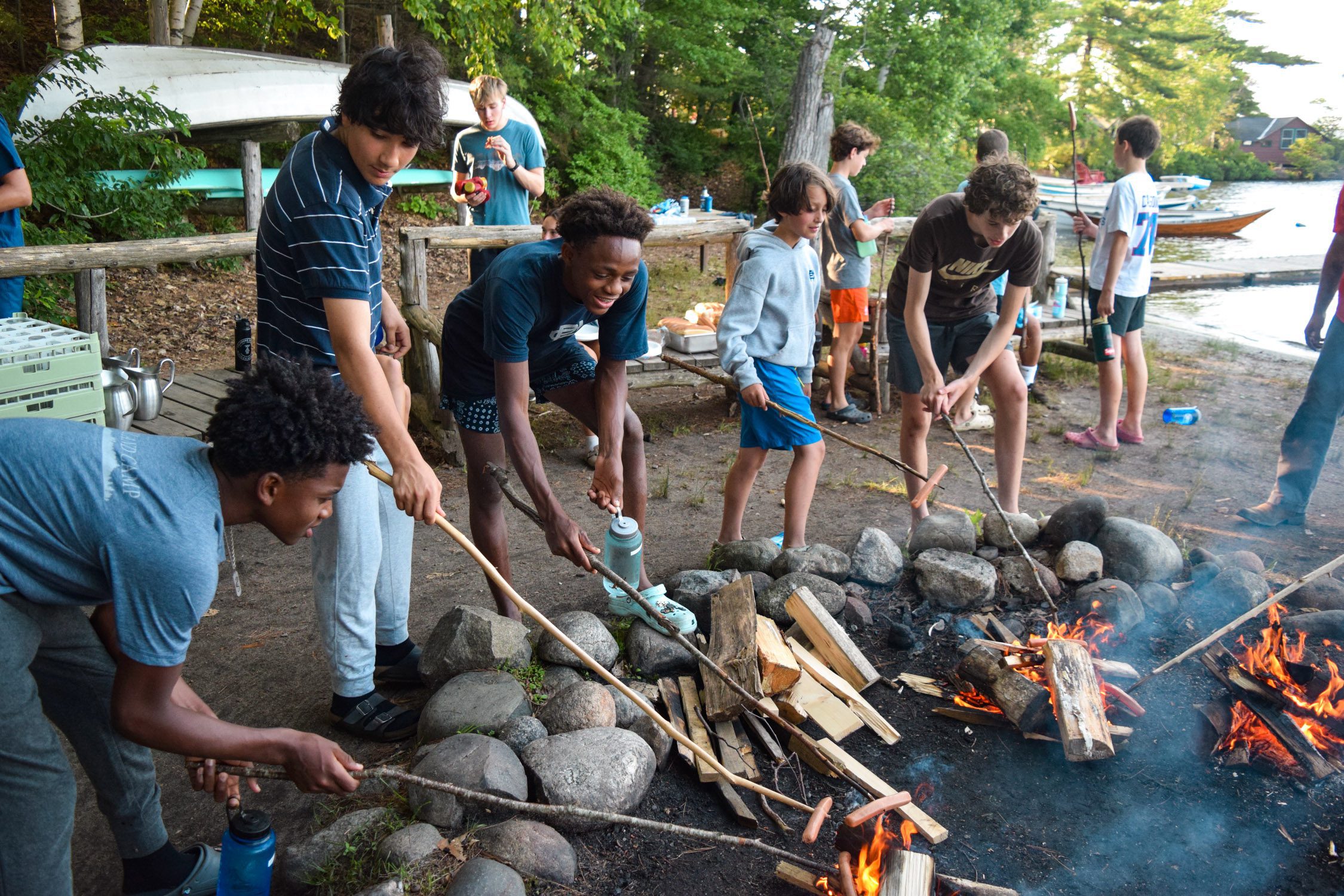 Boys roasting hotdogs around a campfire